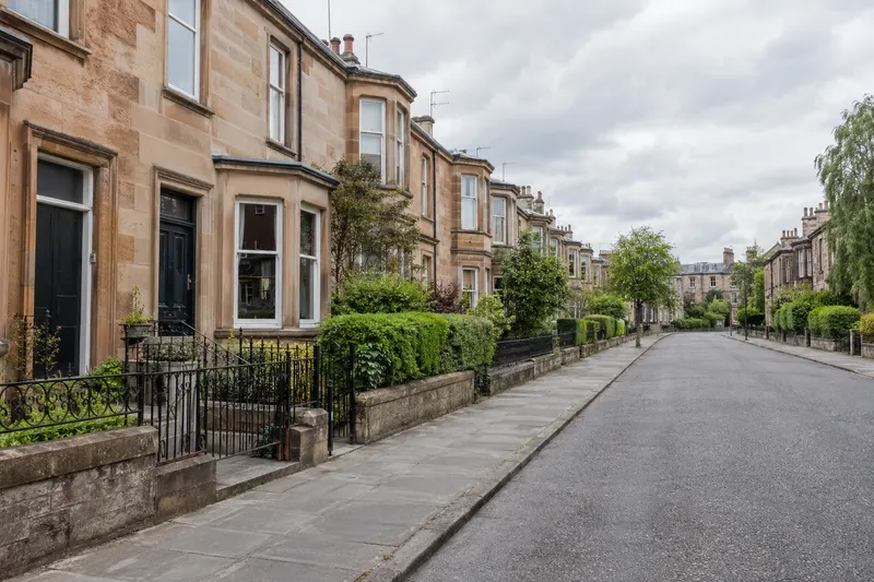 Clear pavement on a narrow residential street lined with sandstone houses